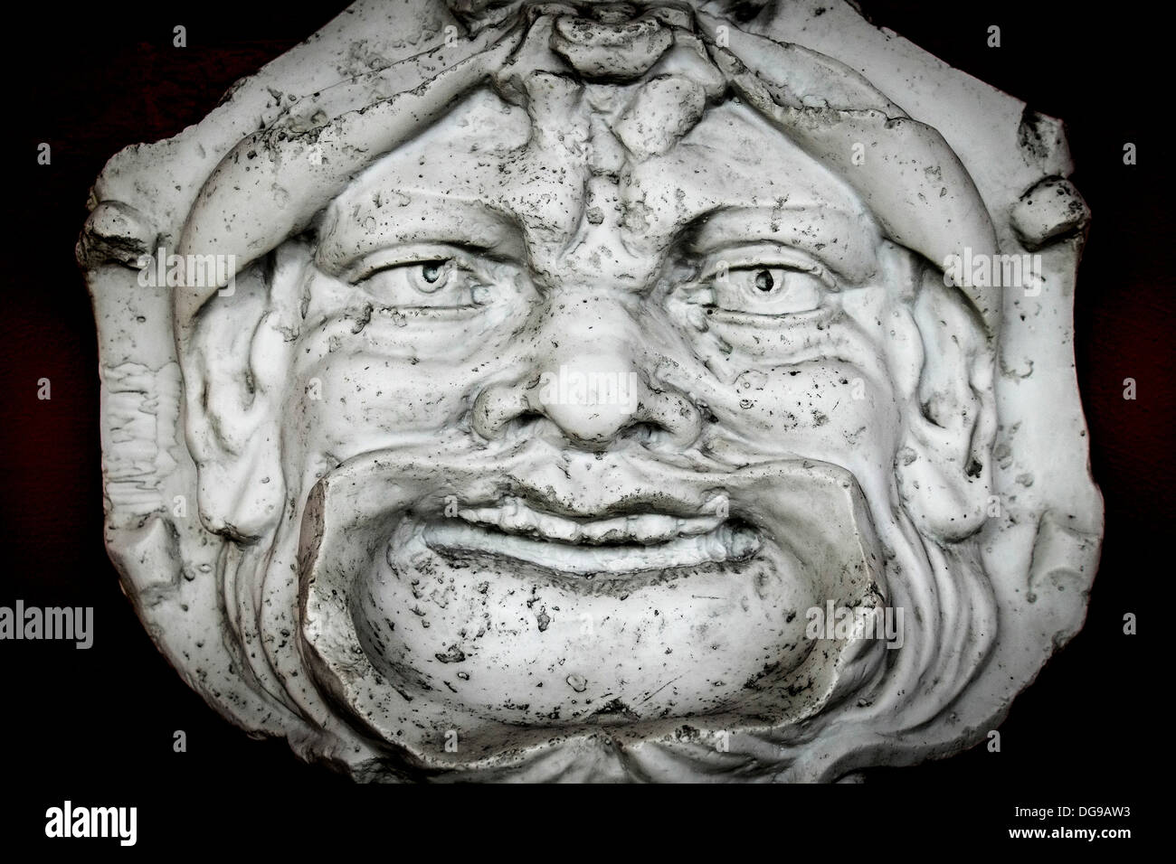 Una piedra tallada de un rostro feo. Foto de stock