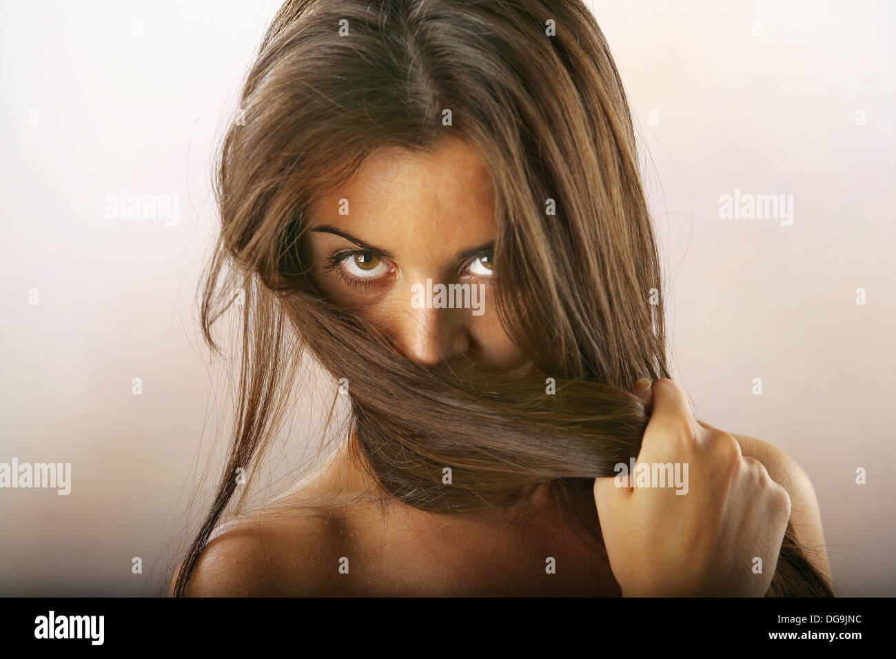 Foto de estudio de chica que cubre su rostro con su largo cabello. Foto de stock