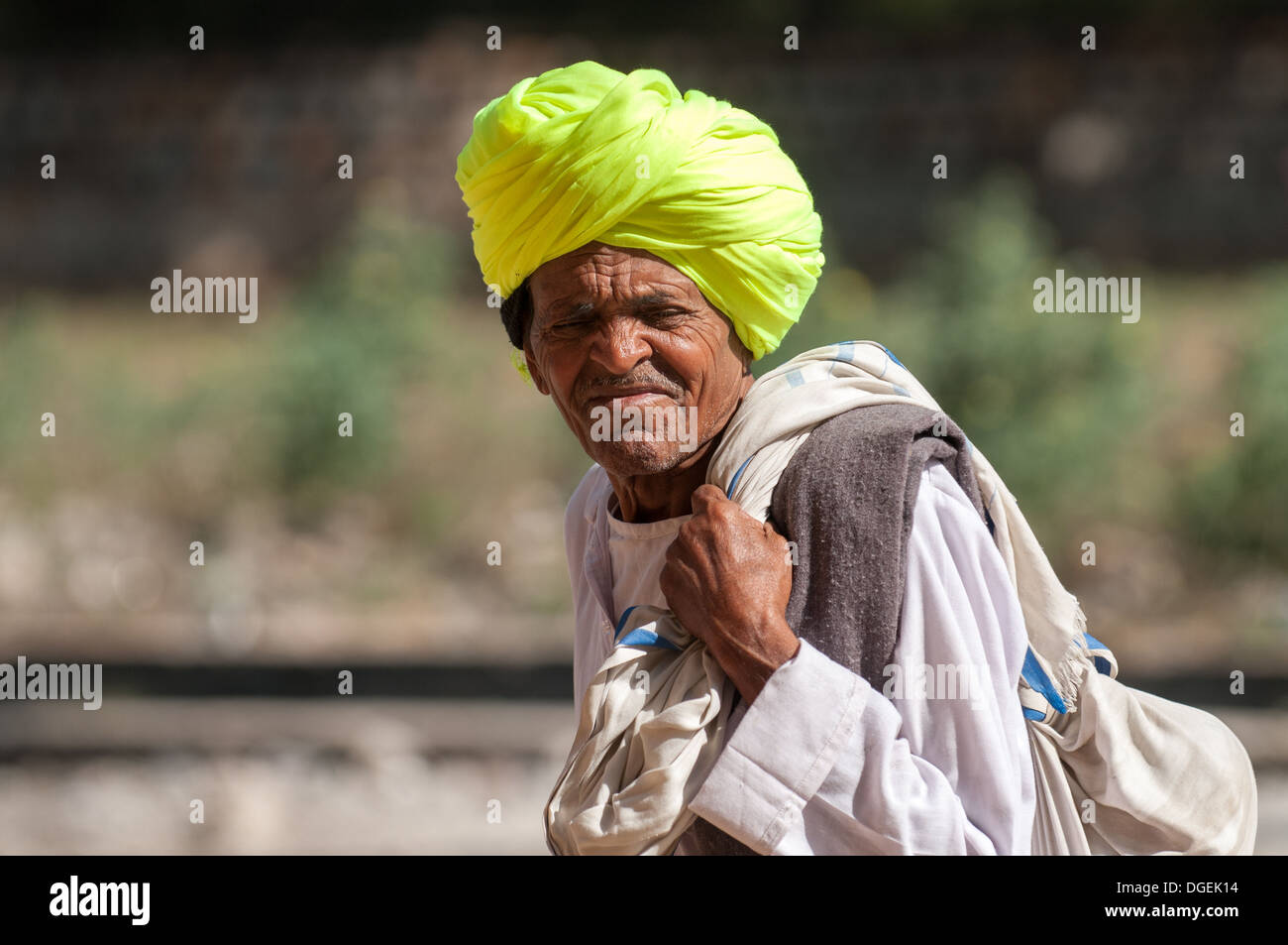 Hombre de Rajasthani en amarillo turbante lleva un saco en Ranthambore, India. Foto de stock