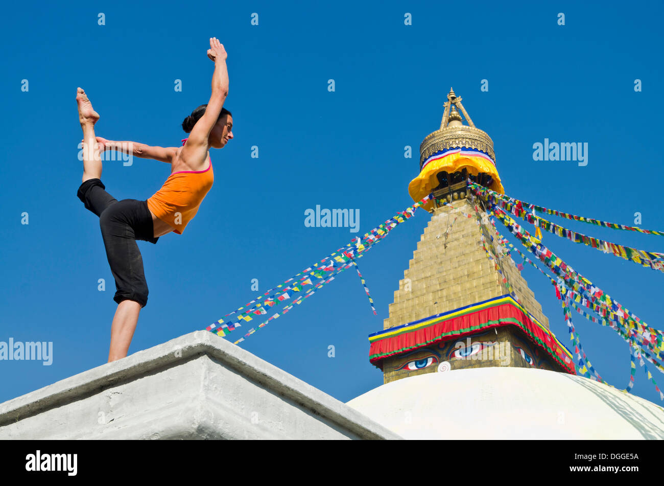 Mujer joven practicando yoga en Boudnanath stupa, mostrando el Natarajasana pose o postura del Señor Shiva, el Valle de Katmandú Foto de stock