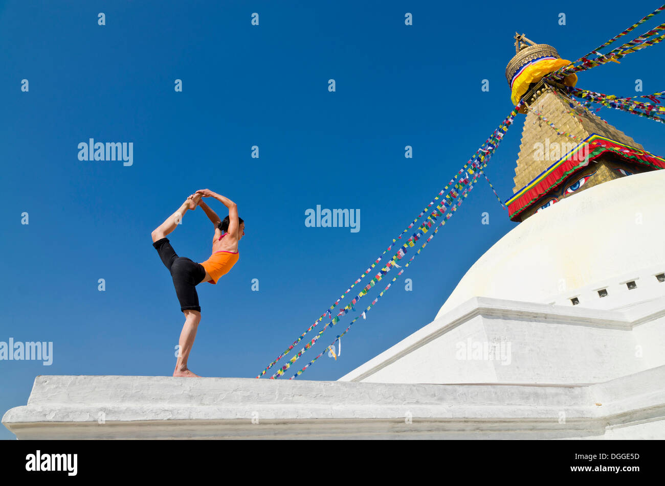Mujer joven practicando yoga en Boudnanath stupa, mostrando el Natarajasana pose o postura del Señor Shiva, el Valle de Katmandú Foto de stock
