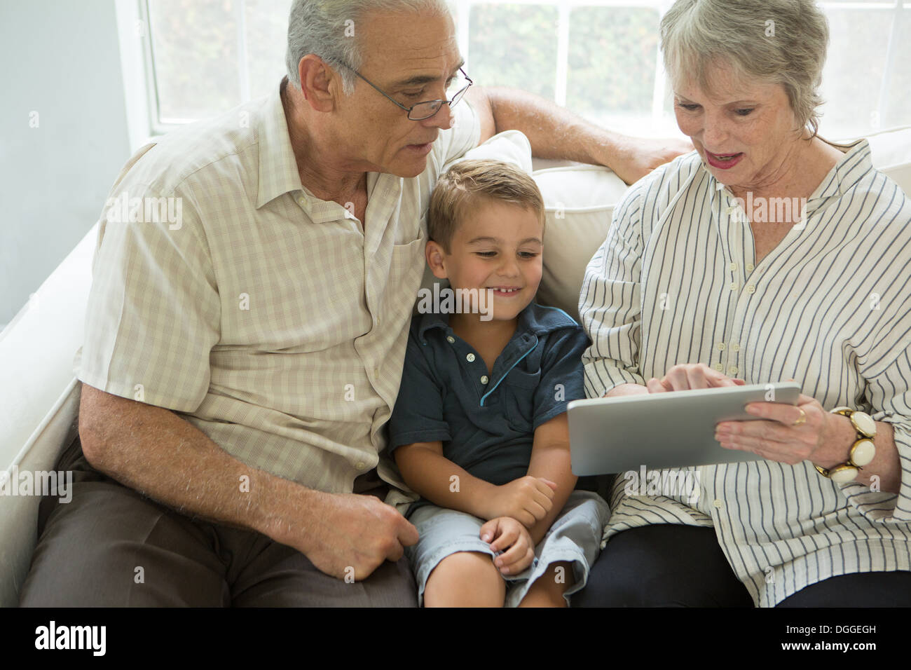 Los abuelos mostrando tableta digital boy en el sofá Foto de stock