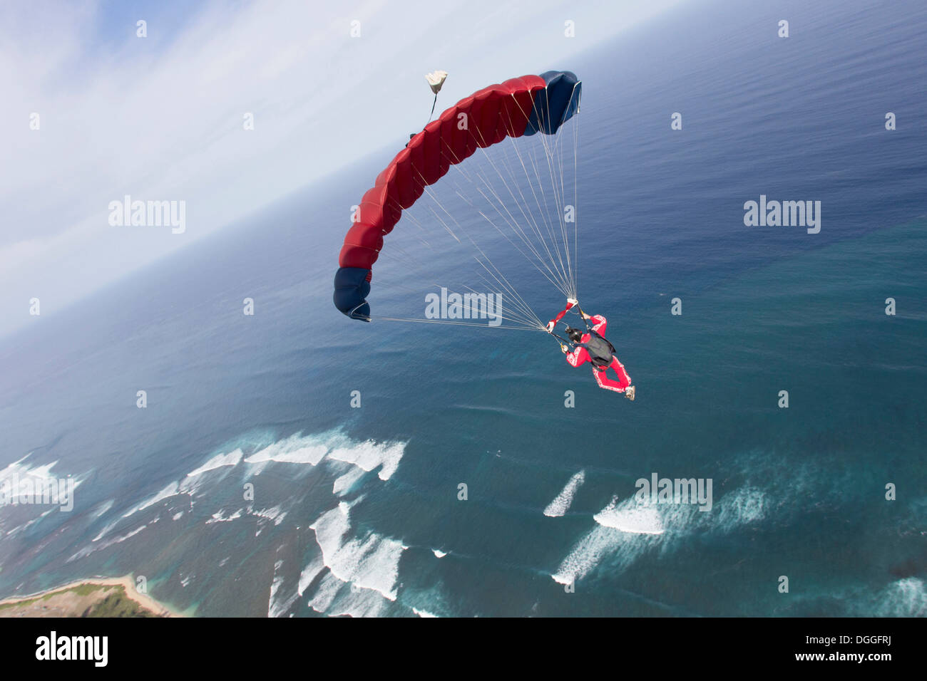 Paracaidista con paracaídas rojo encima de Honolulu, Hawai Foto de stock