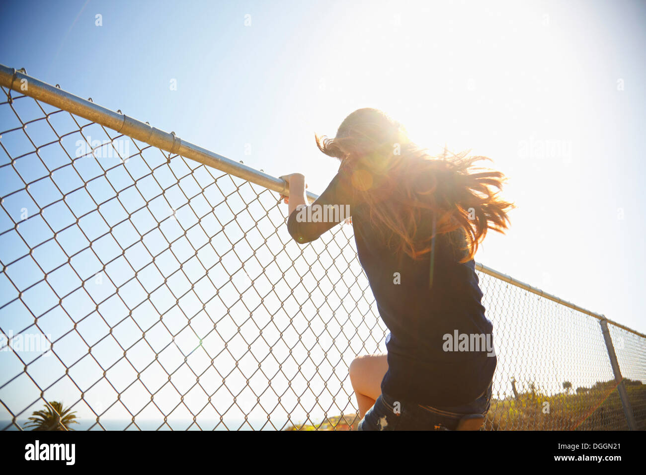 Mujer joven jugando en la valla de alambre Foto de stock
