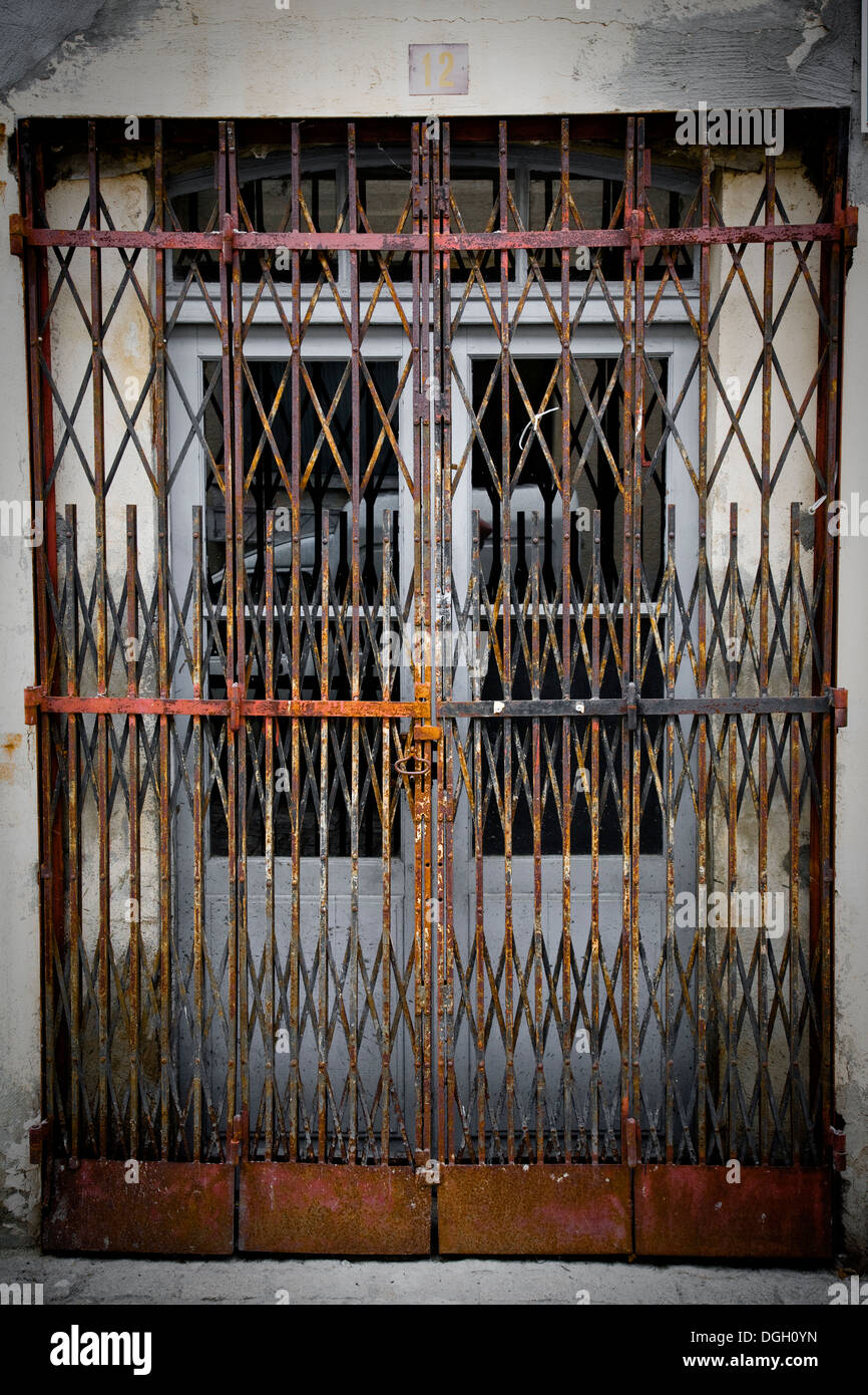Puertas de metal oxidado tipo acordeón bloqueado delante de un par de  puertas Fotografía de stock - Alamy
