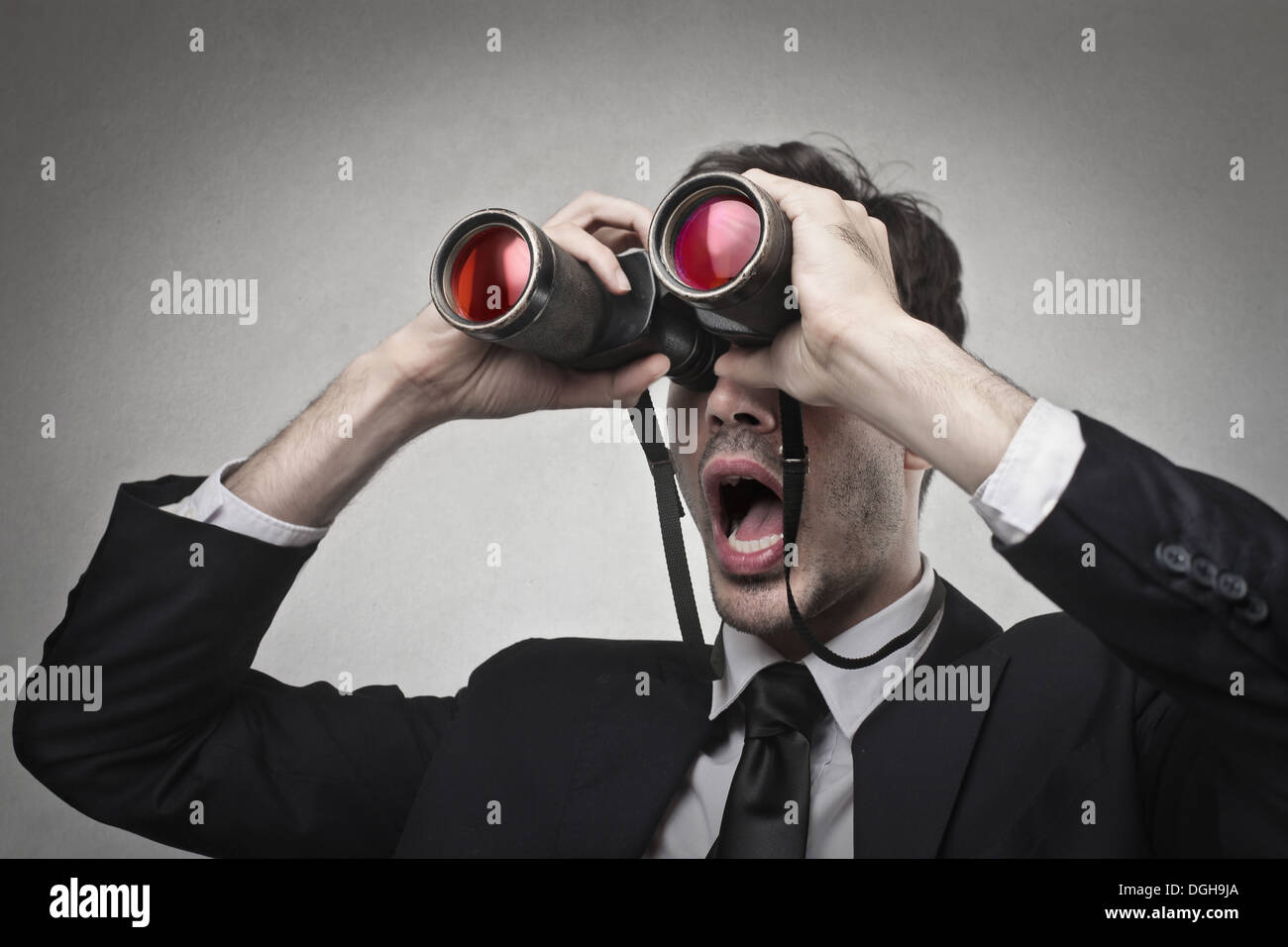 Sorprendido el empresario mirando a través de binoculares algo Foto de stock