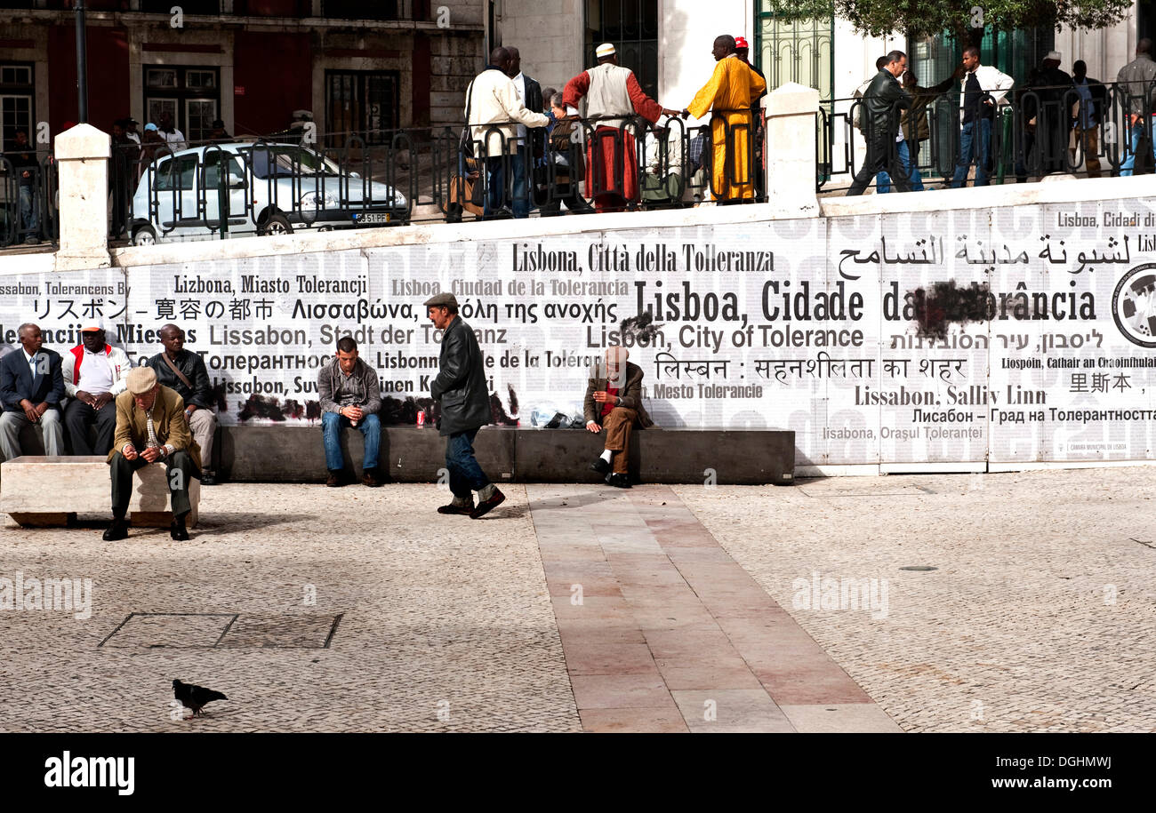 La gente en una plaza central, llama a la tolerancia en una pared detrás, Portugal, Europa Foto de stock