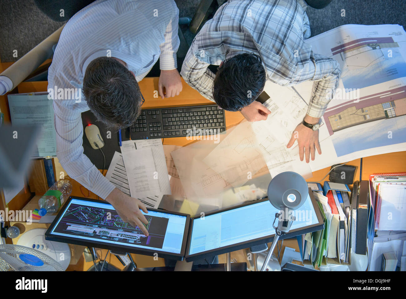 Los arquitectos que trabajan juntos en planes y pantallas de escritorio Foto de stock