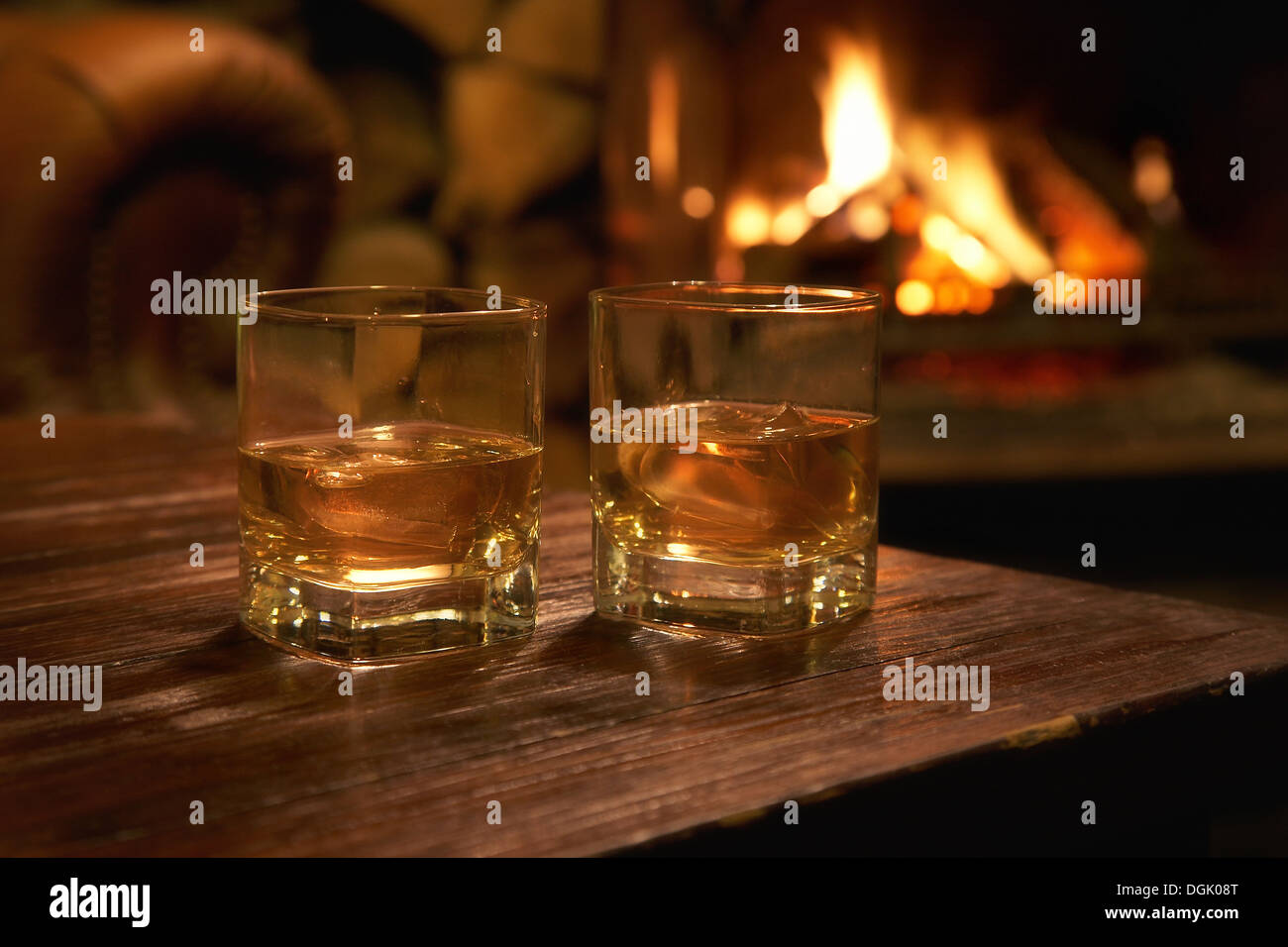 Dos vasos de whisky en una tabla con un registro fuego ardiendo en el fondo  Fotografía de stock - Alamy