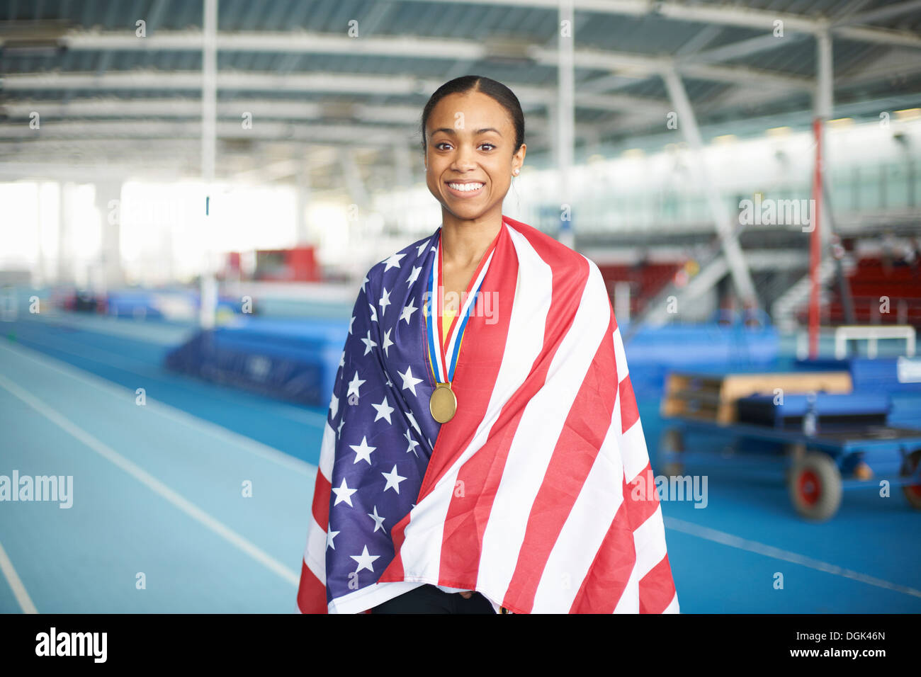 Joven atleta femenina envuelta en la bandera estadounidense con la medalla de oro Foto de stock