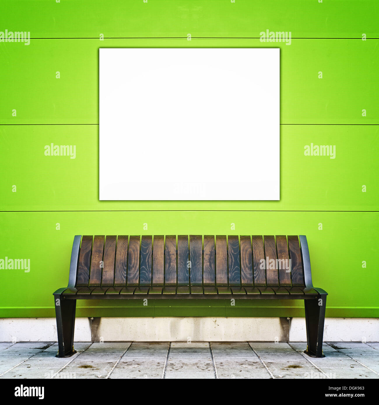 Elegante banco con carteles en blanco contra la muralla verde como fondo Foto de stock