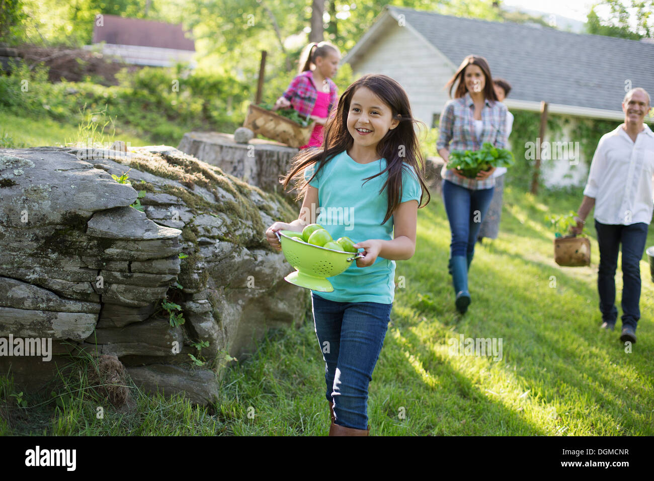 Granja orgánica. Fiesta de verano. Una familia que llevan cestas y cuencos de alimentos a través de la hierba. Foto de stock