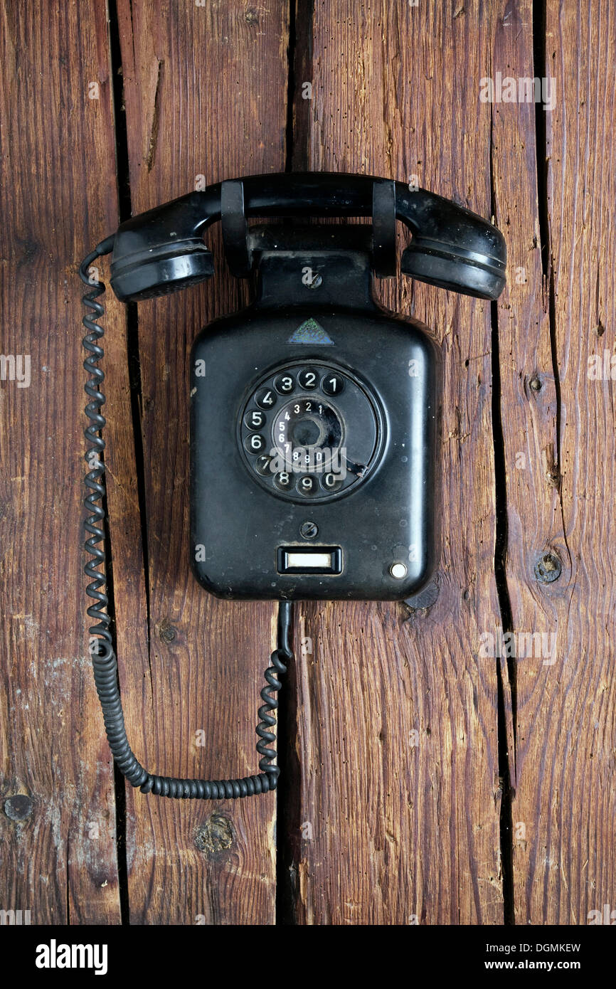 Baquelita Antiguo teléfono de pared desde 1950, colgado en una pared de madera rústica Foto de stock