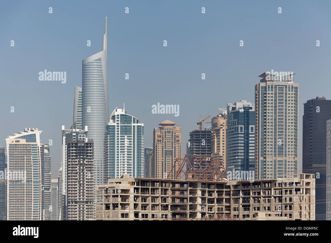 Skyline, Jumeirah Lake Towers y un sitio de construcción interrumpida con el edificio shell, Dubai, Emiratos Árabes Unidos. Foto de stock