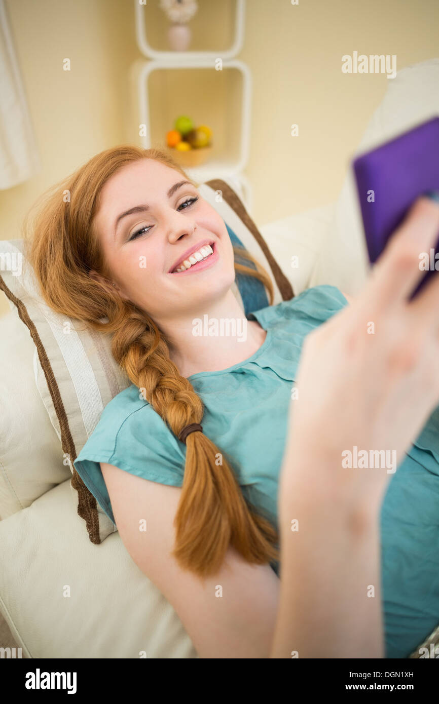Feliz redhead tumbado en la cama enviando un mensaje de texto Foto de stock