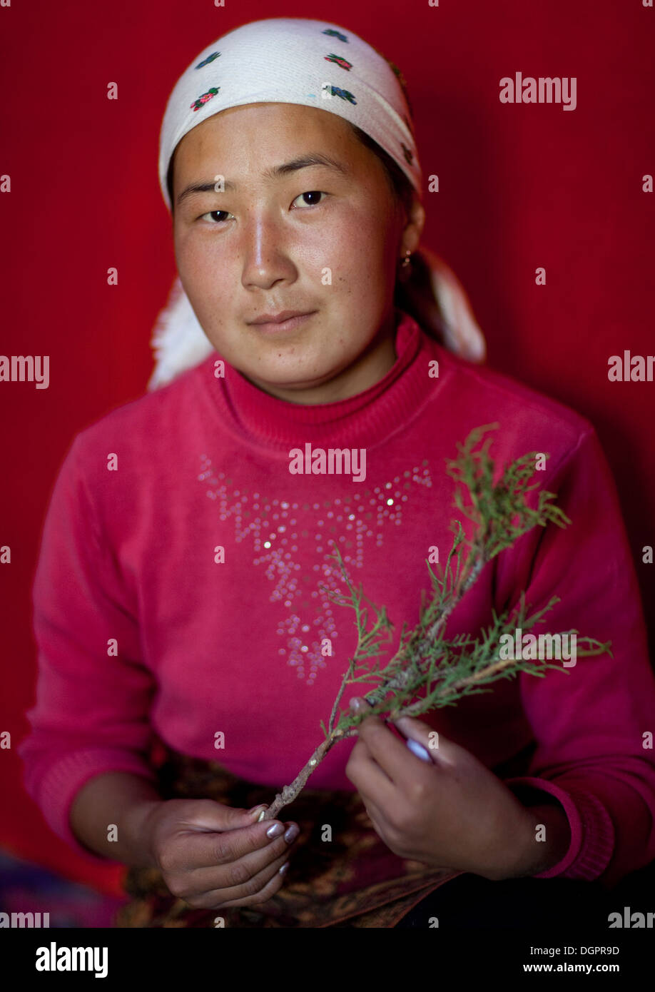 Mujer con velo mostrando una hierba aromática, Jaman Echki Jailoo Village, Kirguistán Foto de stock