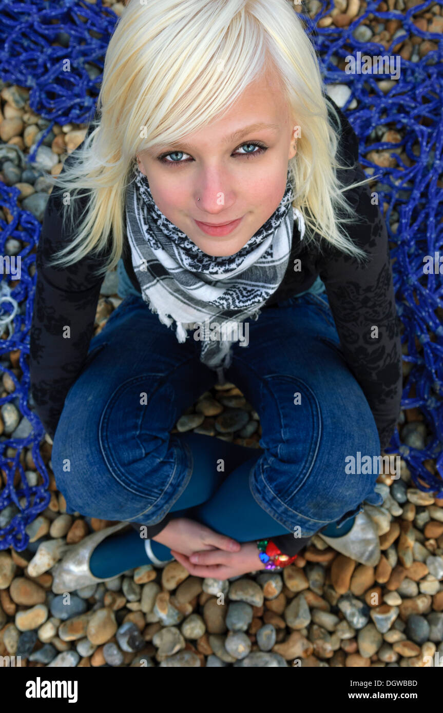 Rubia adolescente sentado en una playa de guijarros y mirando la cámara Fotografía de stock Alamy