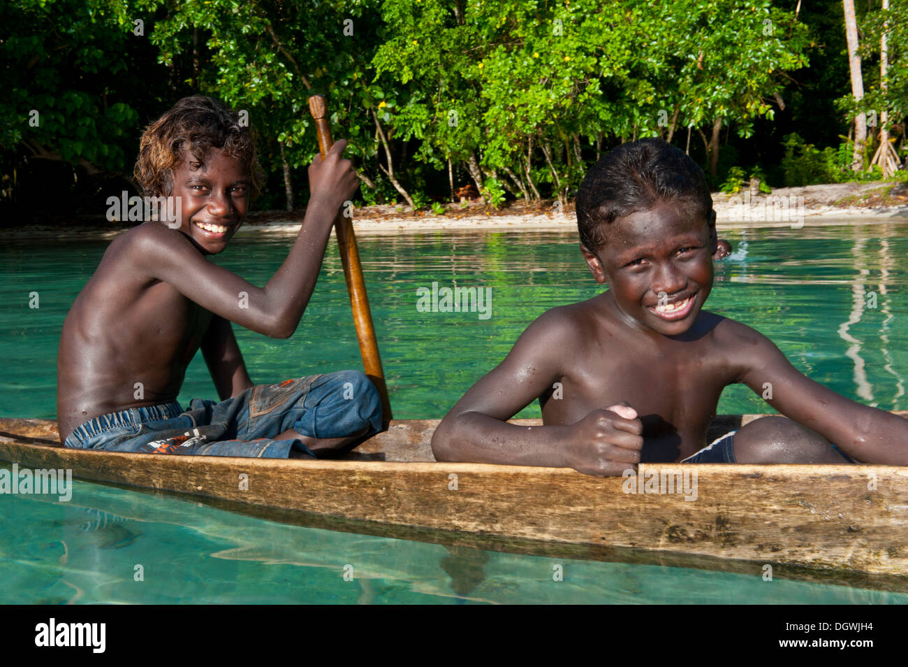 Los chicos locales en una canoa en la Laguna Marovo, Islas Salomón Foto de stock