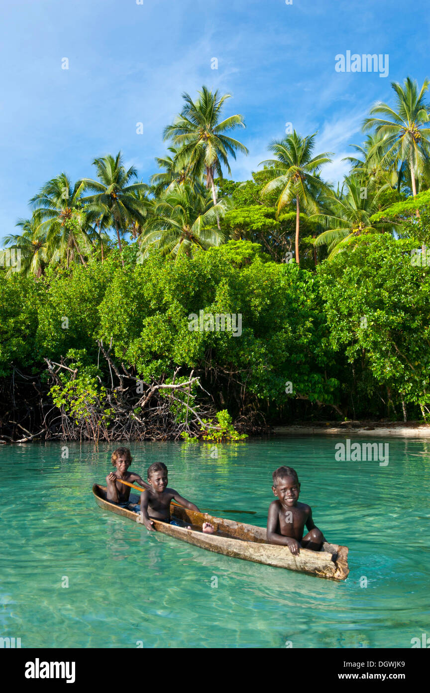 Los chicos locales en una canoa en la laguna de Marovo, Marovo Lagoon, en la provincia occidental, las Islas Salomón Foto de stock