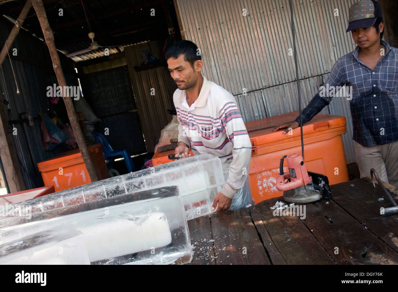 Un hombre está trabajando con grandes bloques de hielo en un almacén de entrega de hielo en Kampong Cham, Camboya. Foto de stock