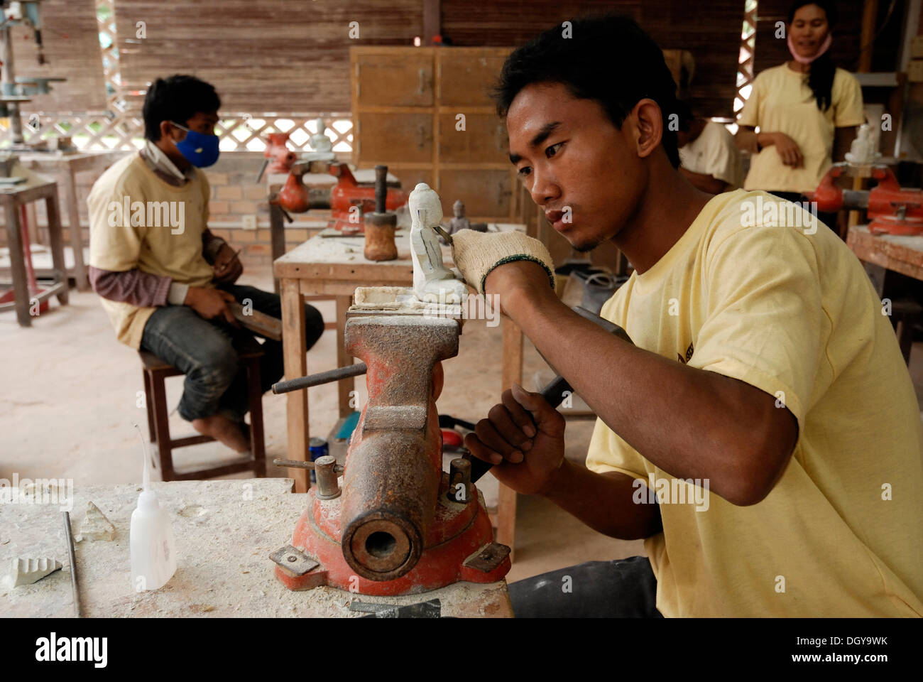 Dos jóvenes artesanos de Camboya durante la artesanía artística de la piedra con un martillo y un cincel de madera para producir un Foto de stock