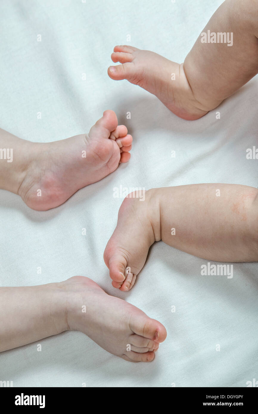 Bebé de 4 meses de edad sentado con los pies descalzos sobre una alfombra.  Juguetes en primer plano Fotografía de stock - Alamy