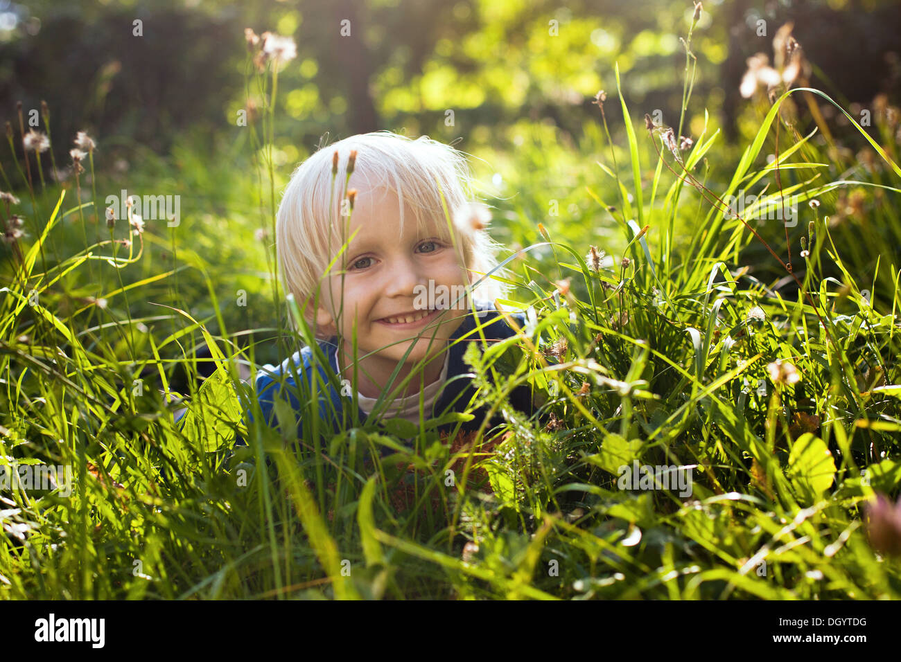 Niñito alegre rubia en la hierba Foto de stock