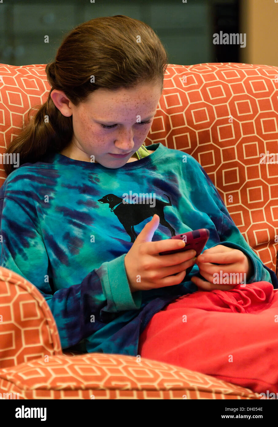 Niña de doce años La lectura de un mensaje de texto en su teléfono móvil. Foto de stock