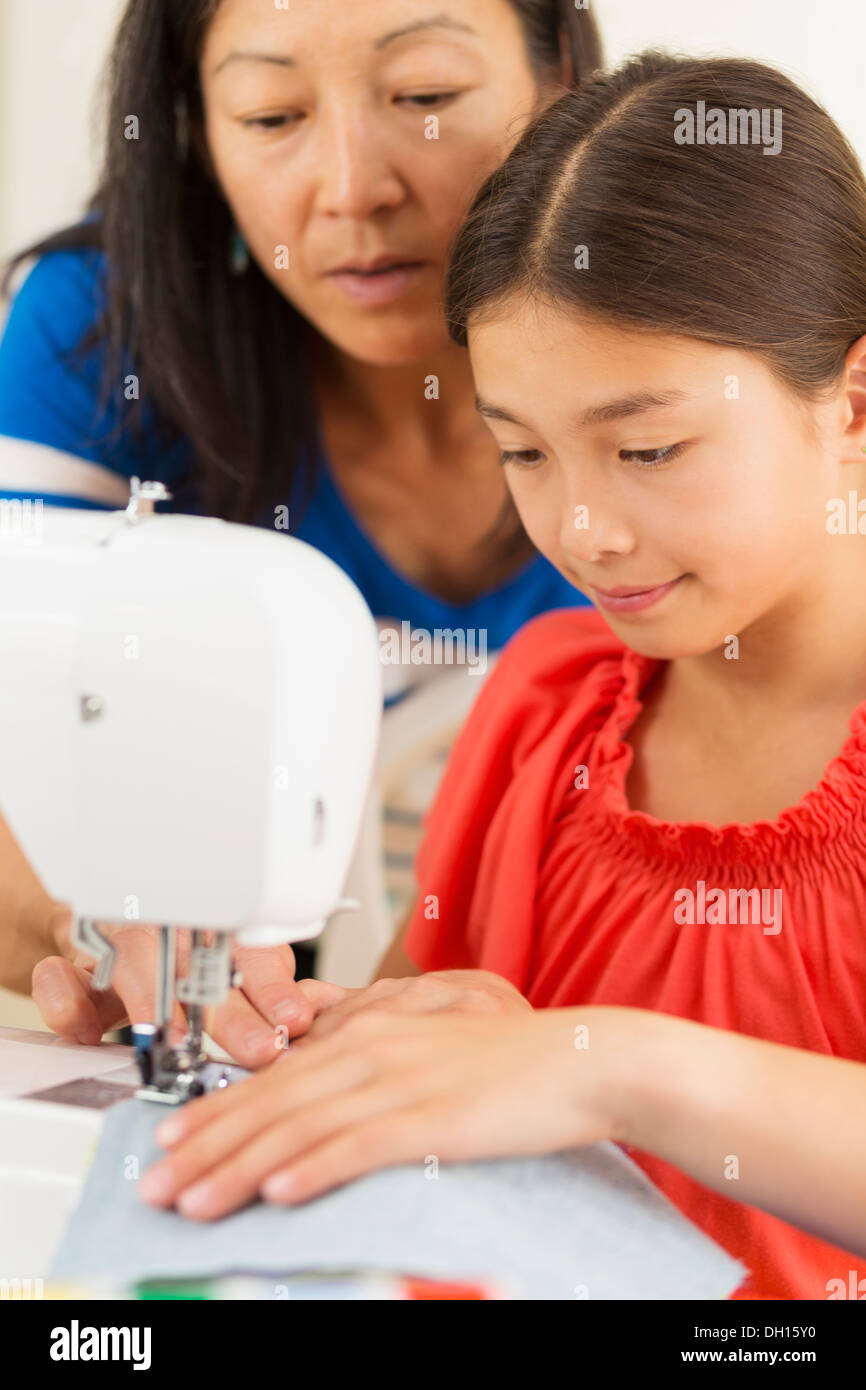 Madre de la enseñanza chica a usar la máquina de coser Foto de stock