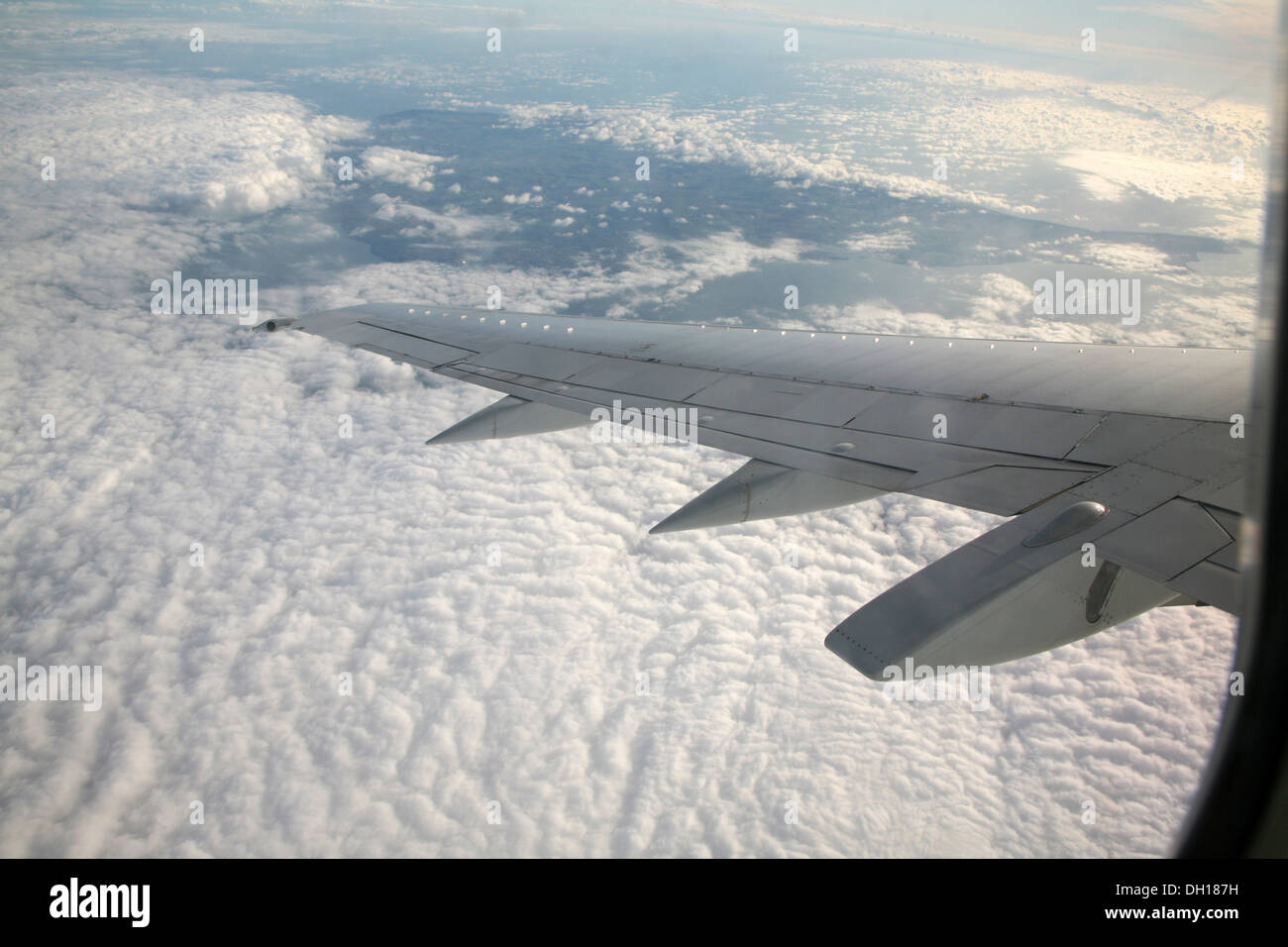 Mirando en la ventana de ala de avión y las nubes debajo Foto de stock