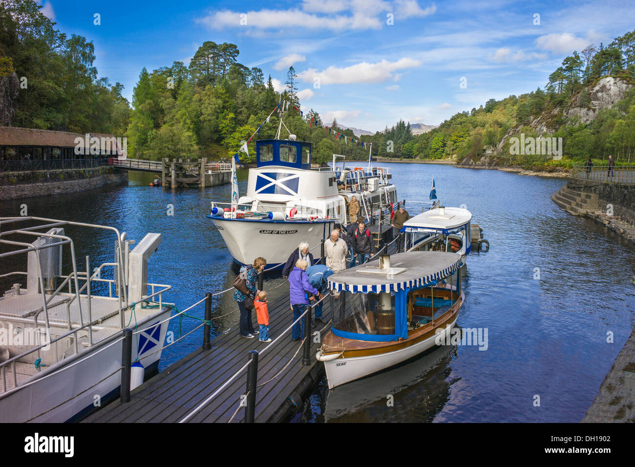 Los pasajeros desembarcan de la embarcación de recreo La dama del lago Loch Katrine en los Trossachs pier pasando pequeños barcos de vapor Foto de stock