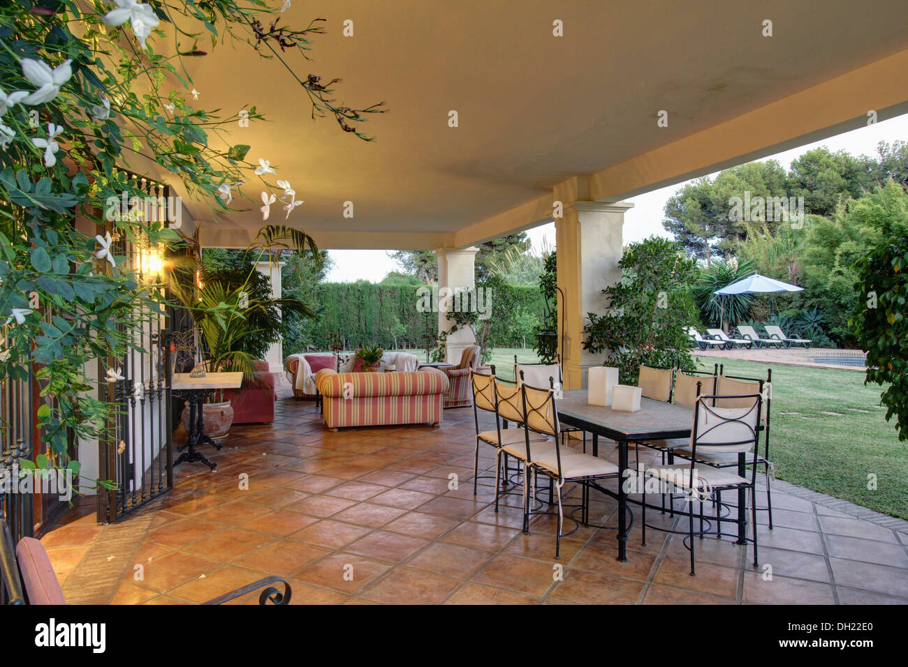 Tabla de metal y sillas con cojines blancos en gran veranda tejas terracota  de villa en el sur de España, con vistas al jardín Fotografía de stock -  Alamy