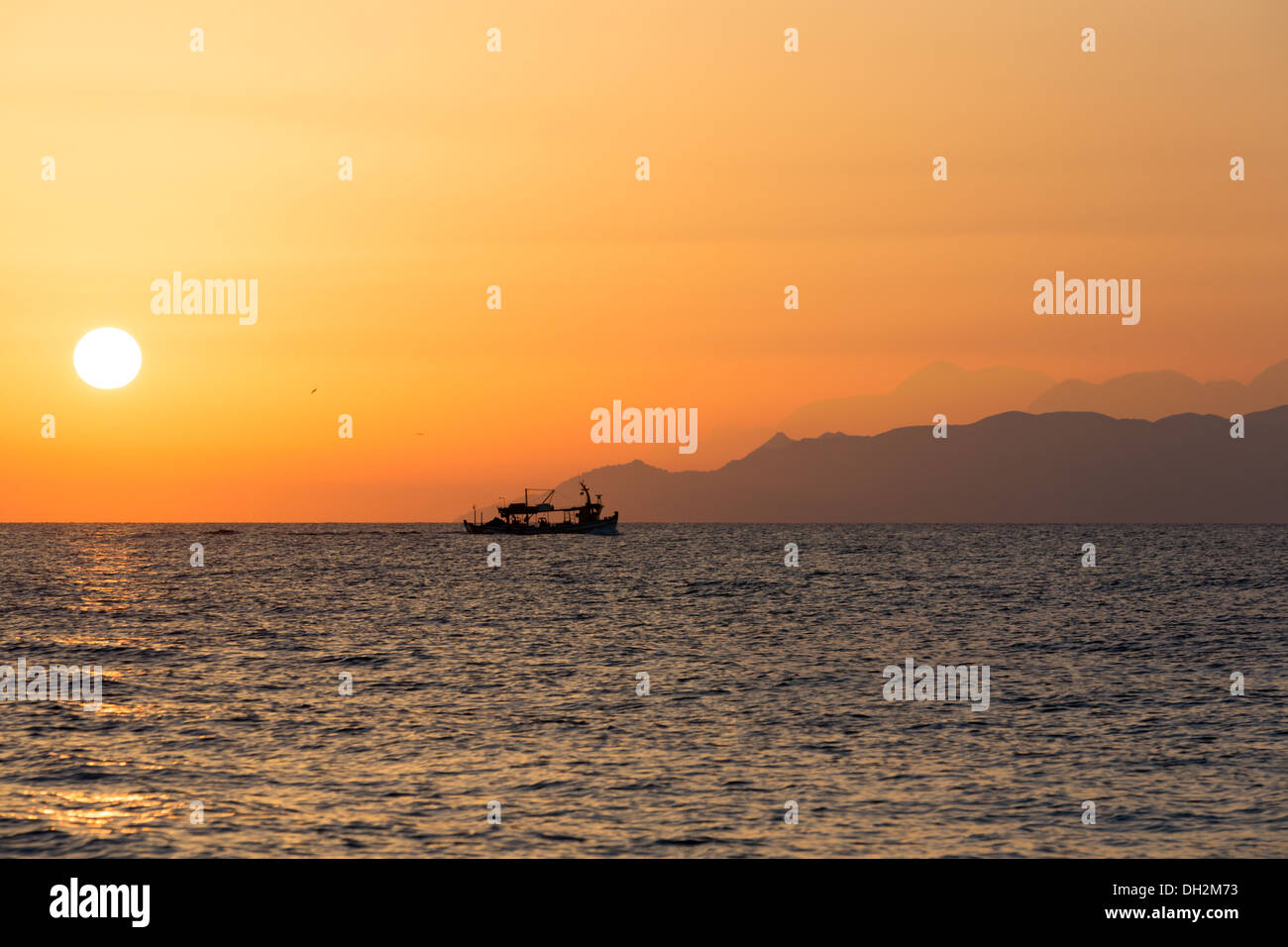El cielo del atardecer en el mar Egeo con el barco y montañas, Santorini Foto de stock