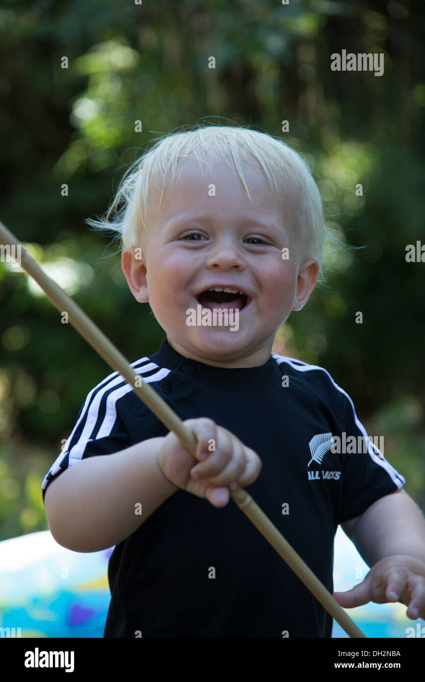 Un niño feliz jugando con un palo Foto de stock