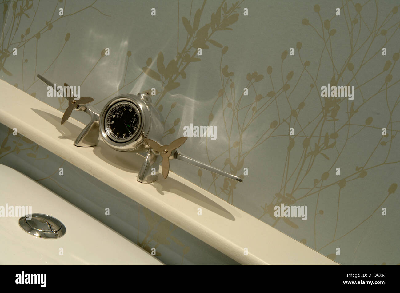 Detalle de un cuarto de baño que muestra un reloj de metal tono Plata que tiene la forma de un avión. Se ha hilado de libre flotación hélices. Foto de stock