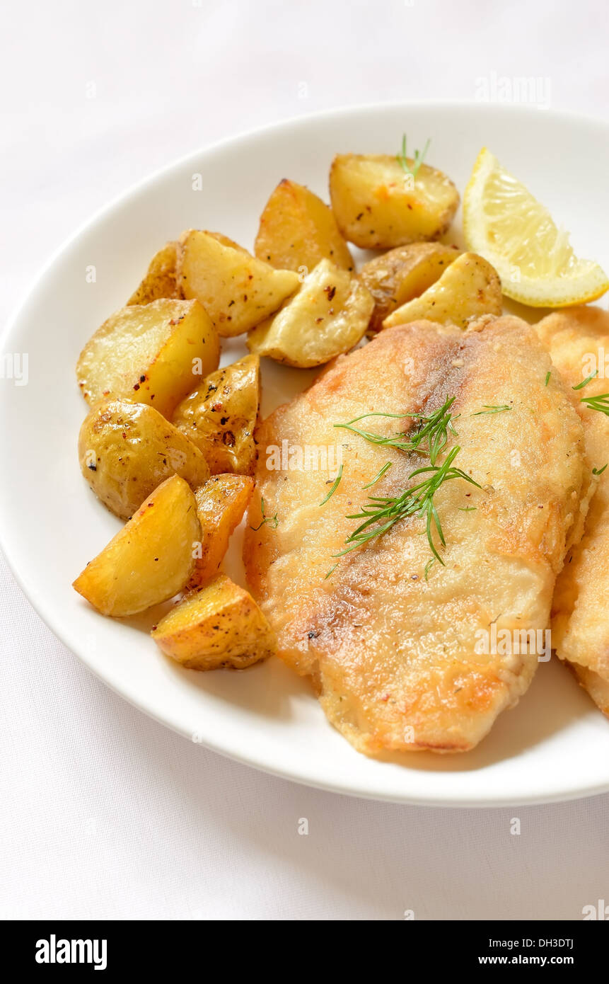 Contracción Mirar furtivamente bruscamente Filete de pescado frito con patatas al horno en la placa blanca Fotografía  de stock - Alamy