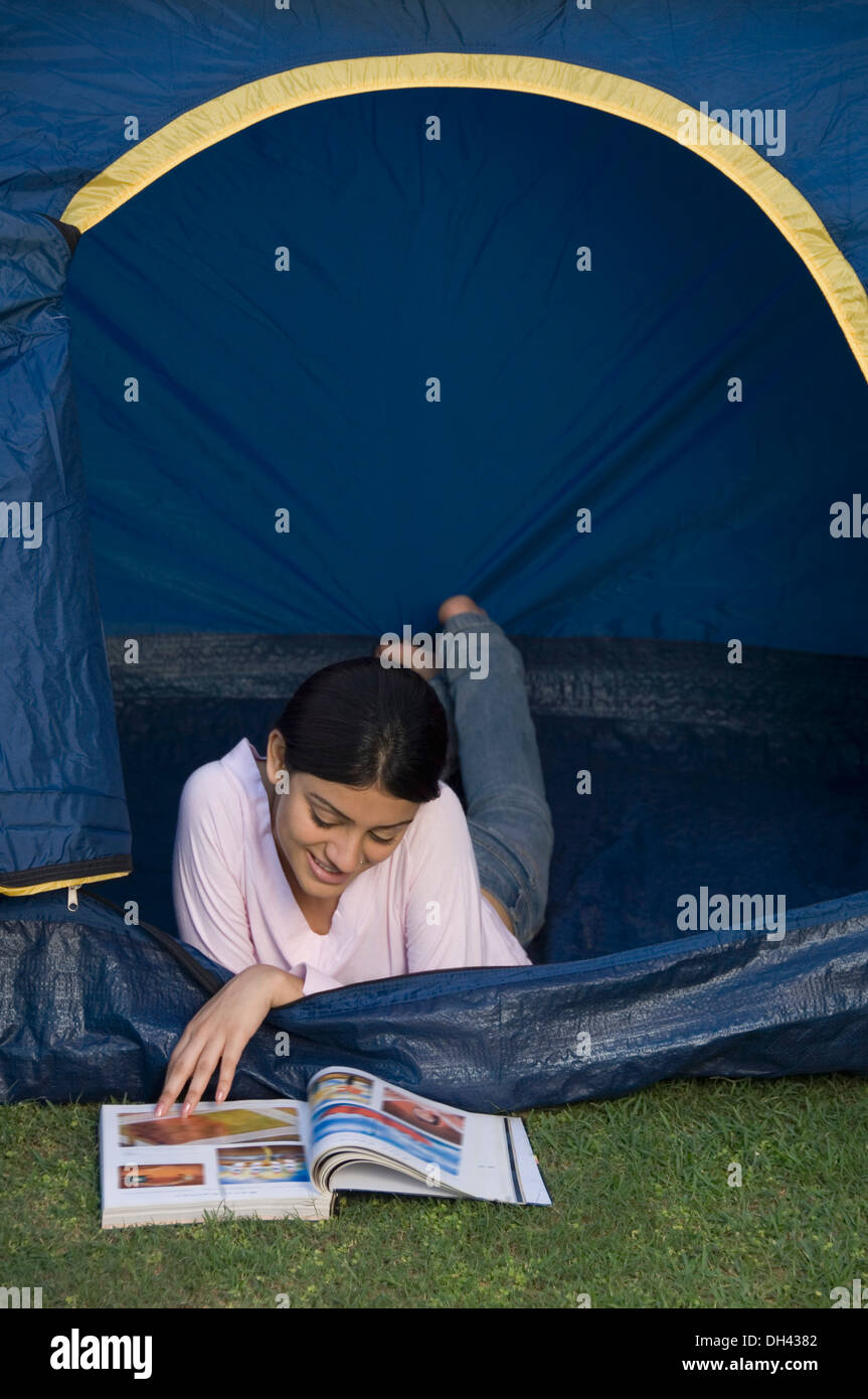 Mujer acostado en una tienda de campaña y leyendo una revista Foto de stock