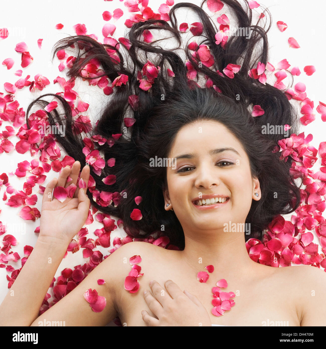 Mujer acostada sobre pétalos de rosas Foto de stock