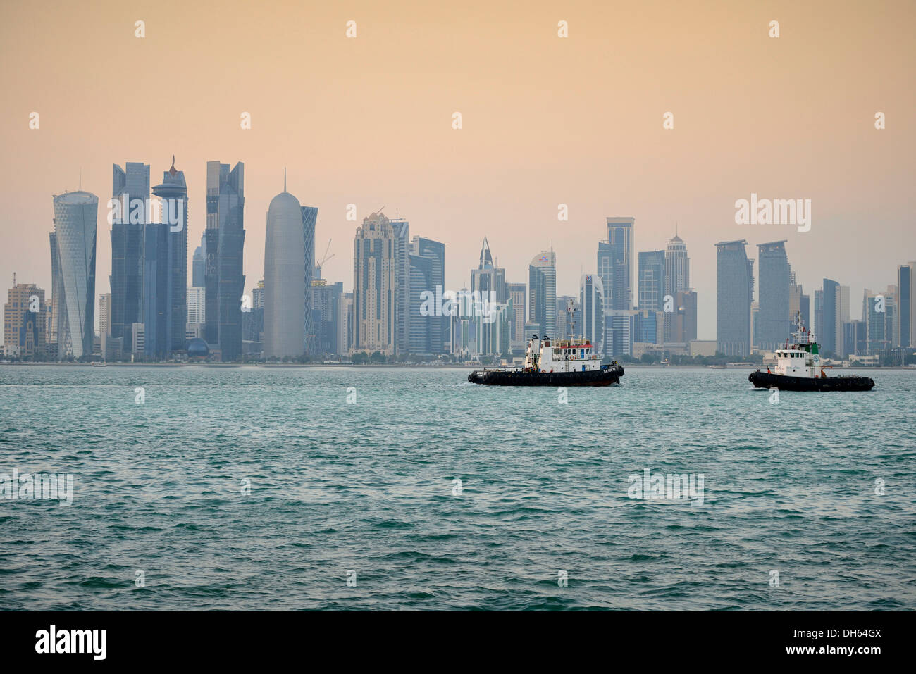 Remolcadores en frente de la ciudad de Doha al anochecer, Doha Corniche, Doha, Doha, Qatar Foto de stock