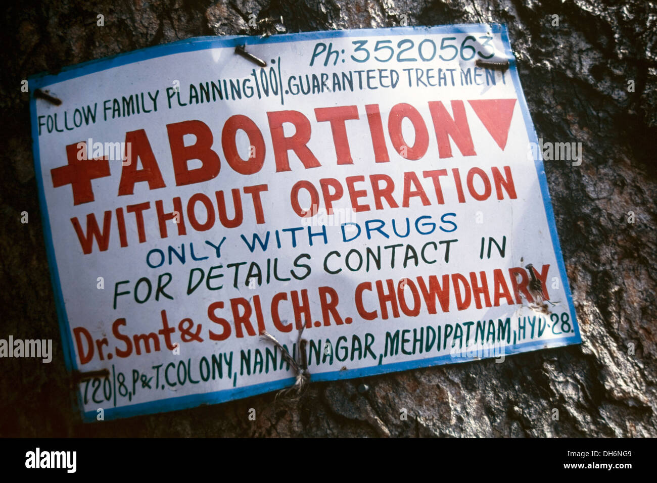 Cartel sobre un árbol publicidad ofreciendo clínicas de abortos sin operaciones usando sólo medicamentos hyderabad india Foto de stock