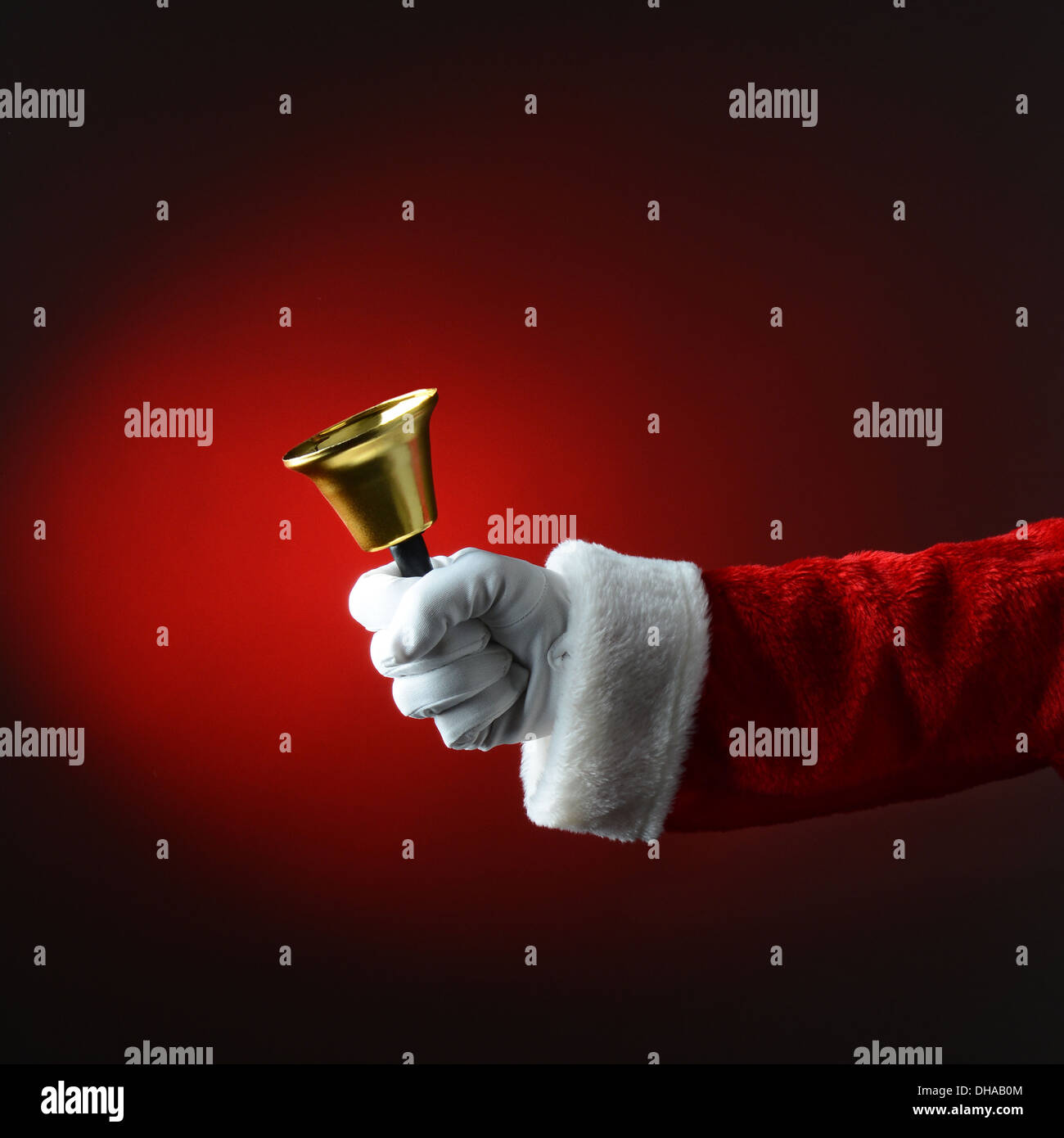 Santa Claus sonando una campana sobre fondo rojo oscuro. Formato cuadrado, sólo son visibles en la mano y el brazo. Foto de stock