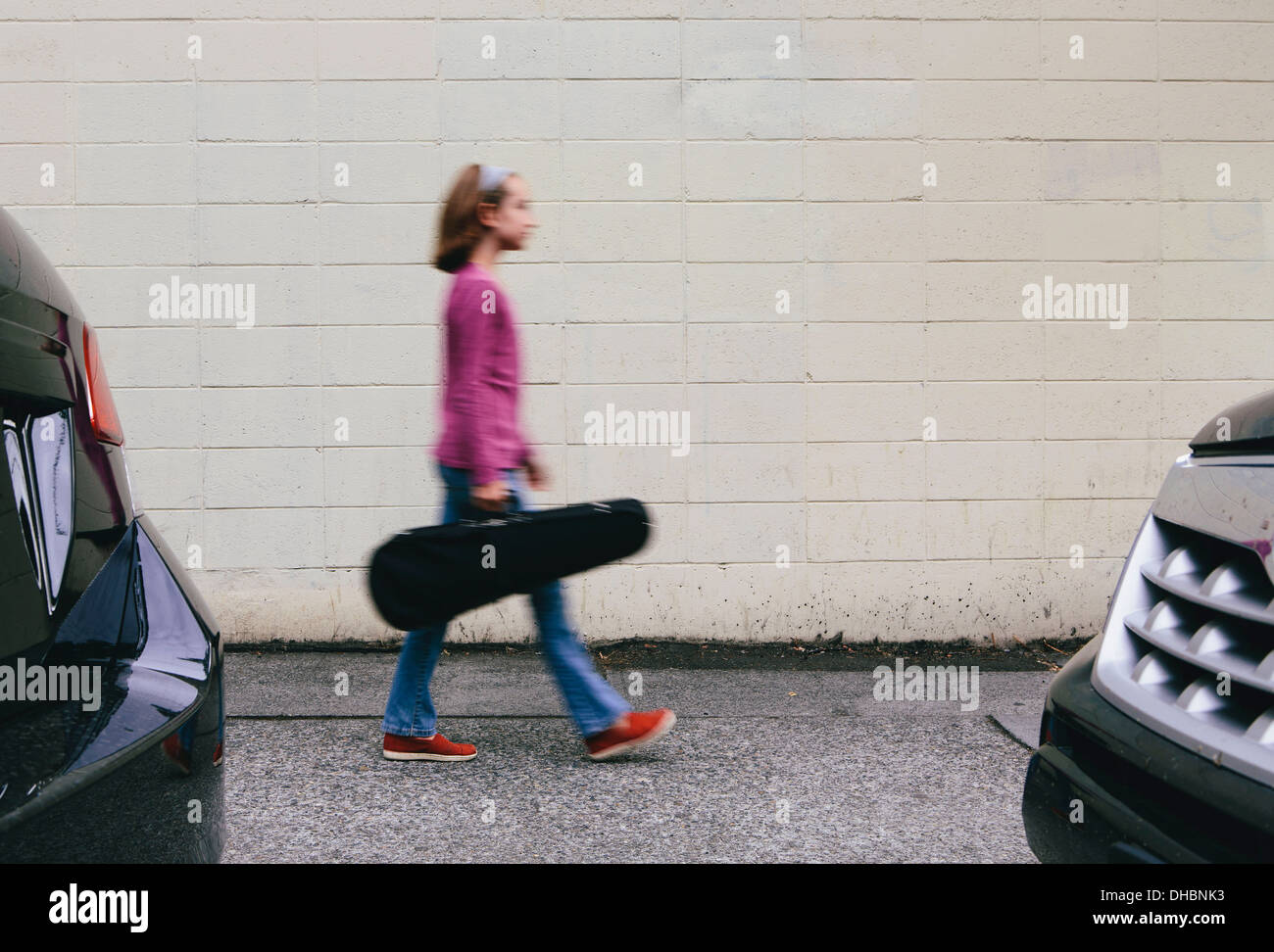 Una niña de 10 años llevando un violín en un caso sobre un trazado urbano. Foto de stock