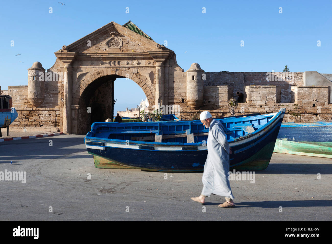 Anciano musulmán caminando debajo de la antigua puerta de la ciudad y murallas, Essaouira, la costa Atlántica, Marruecos, Norte de África, África Foto de stock