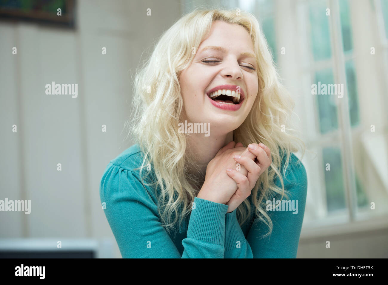Mujer joven feliz con los ojos cerrados y las manos juntas Foto de stock