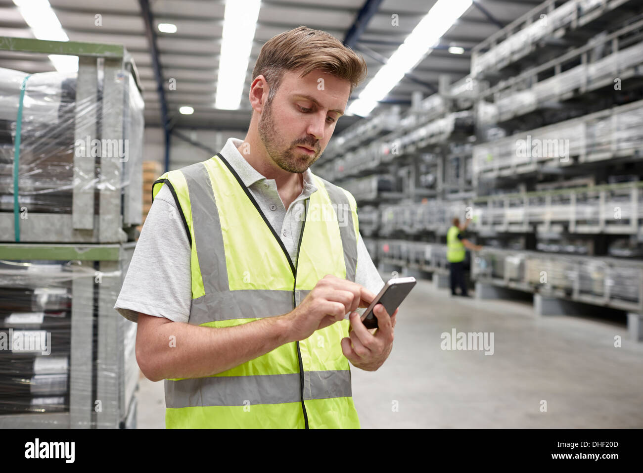 Retrato del trabajador a través de teléfono móvil en el almacén de ingeniería Foto de stock