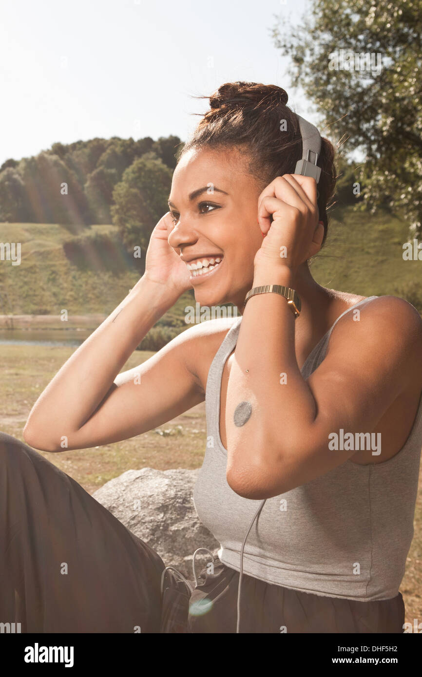 Mujer joven escuchando música en el parque Foto de stock