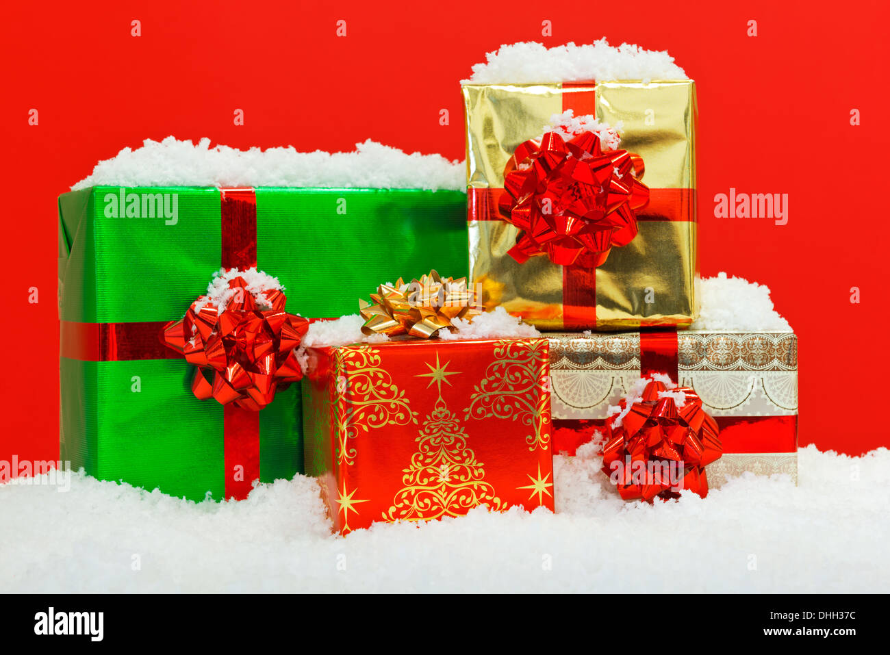 Regalo de navidad envuelto regalos en la nieve con fondo rojo. Foto de stock