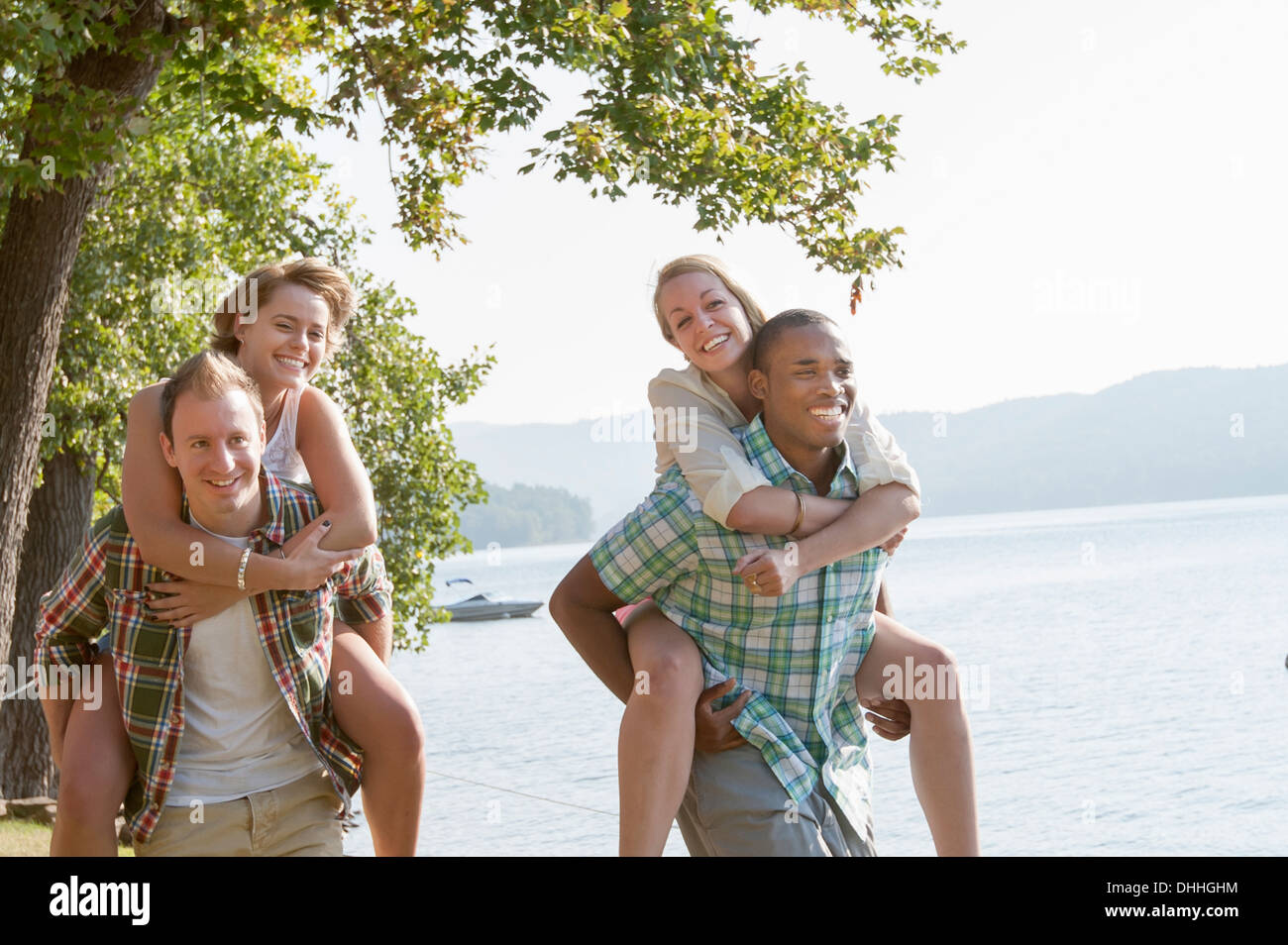 Dar a las mujeres los hombres jóvenes piggy backs Foto de stock