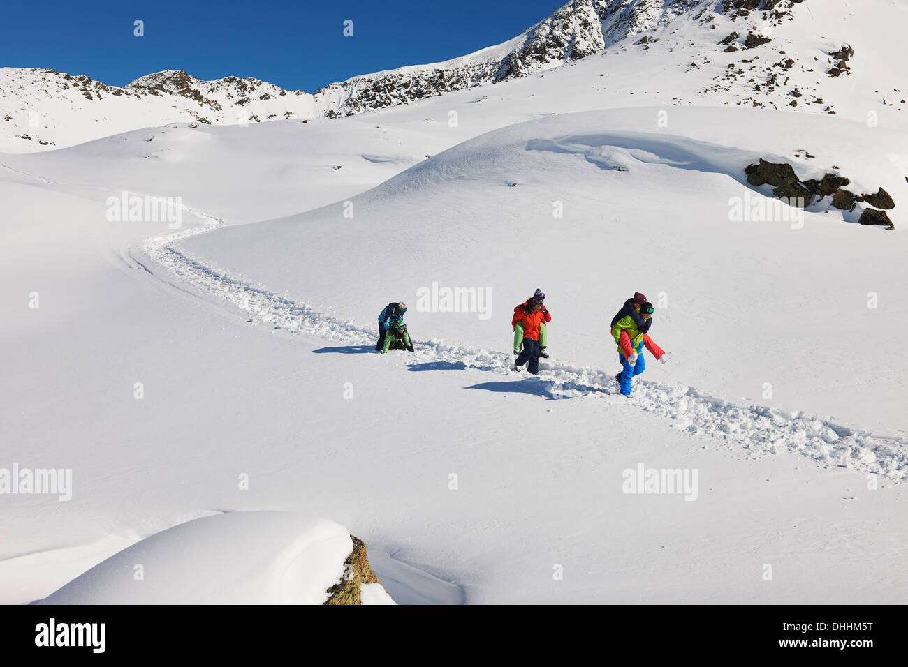 Amigos dándose mutuamente piggy backs en nieve, Kuhtai, Austria Foto de stock