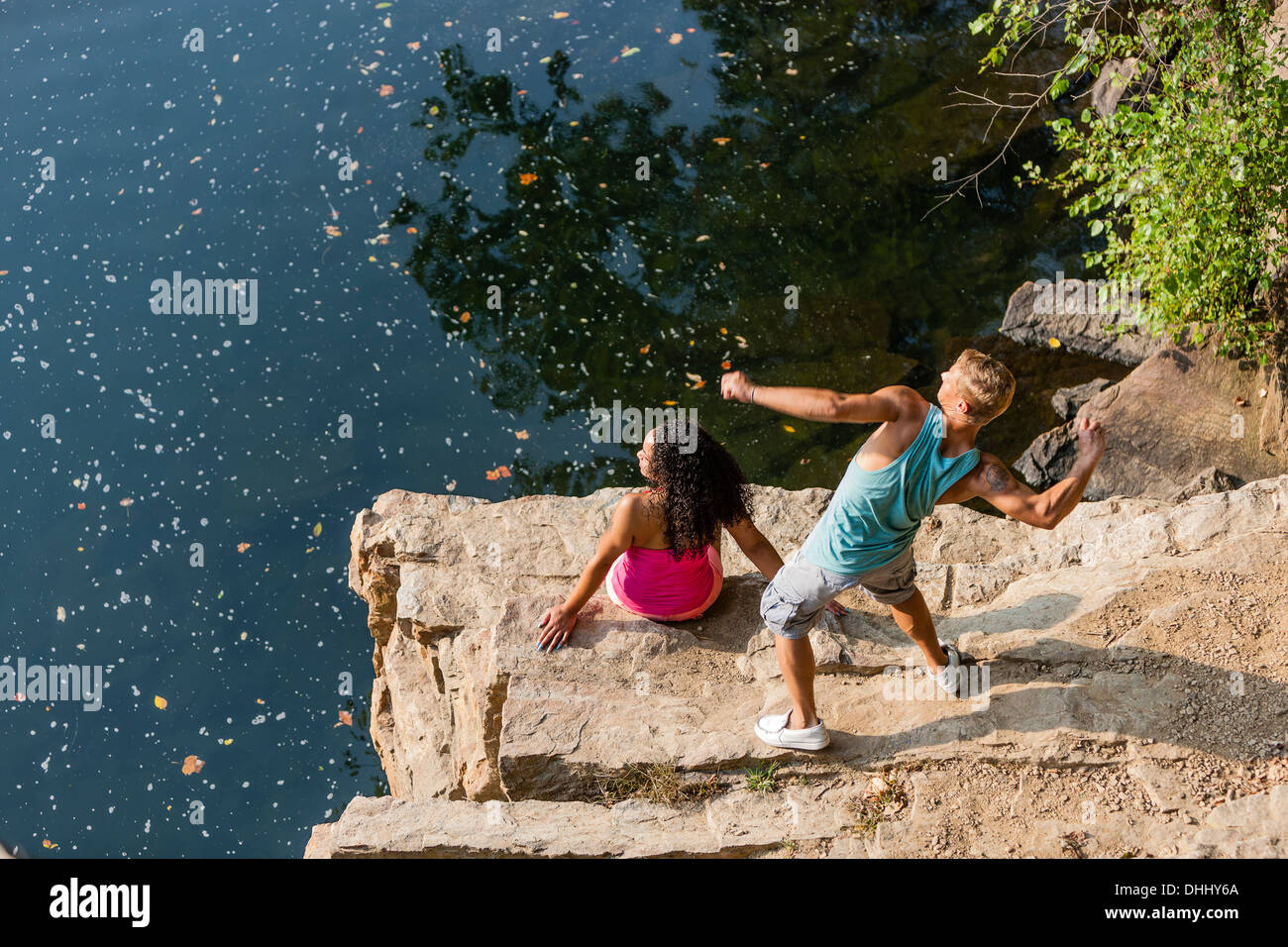 Pareja joven arrojando piedras desde rock ledge, Hamburgo, Pennsylvania, EE.UU. Foto de stock